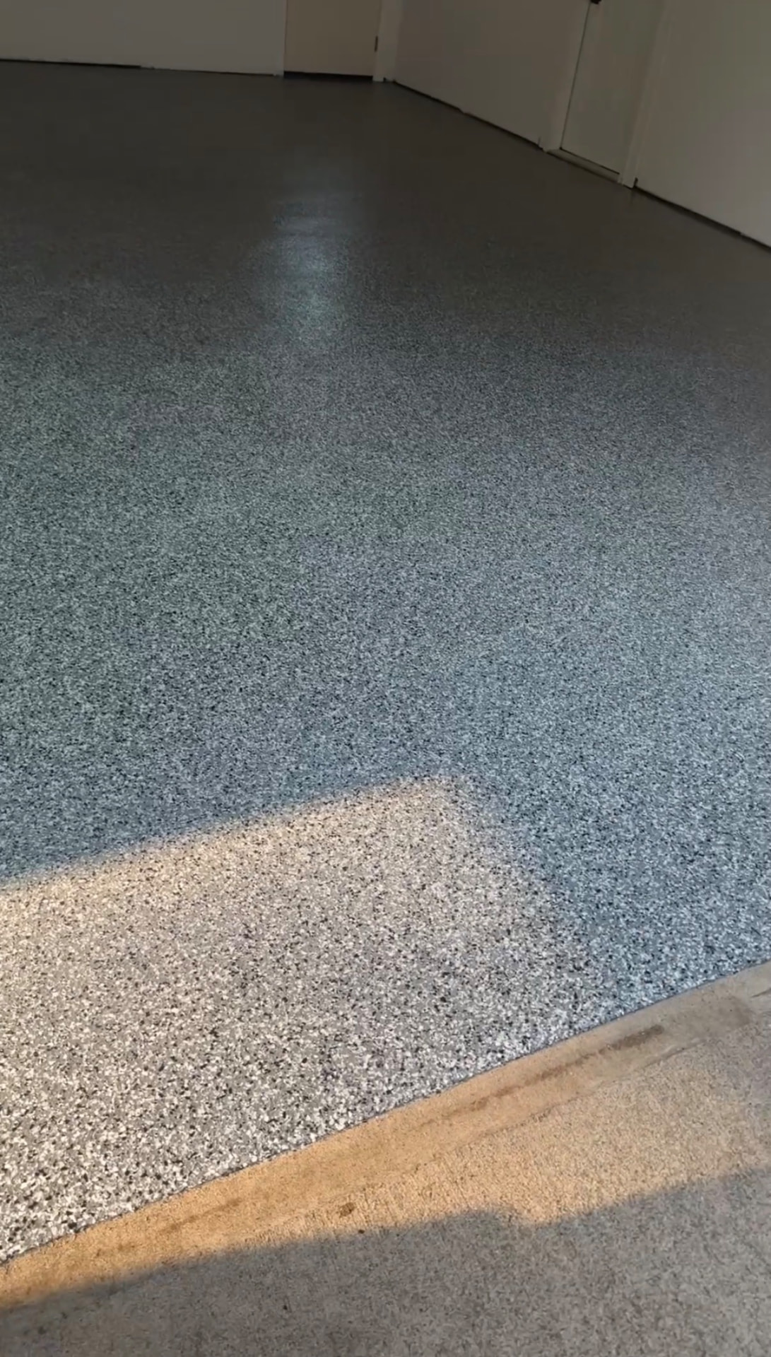 Blue and gray flake epoxy garage floor meeting the concrete apron